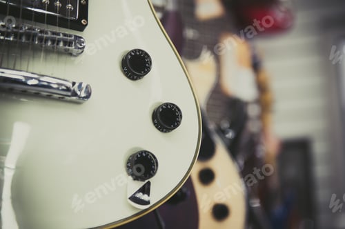 Preview: White Electric Guitar Body And Knobs Detail, Out Of Focus Store Showroom In Background