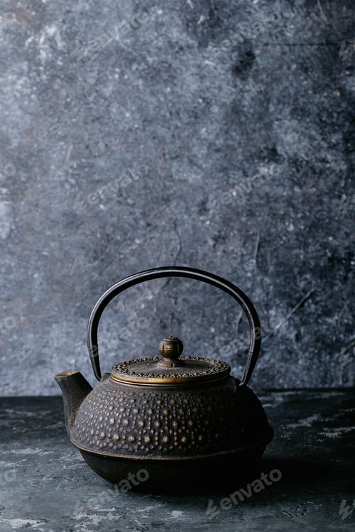 Preview: A Black Metal Teapot And A Black Tea Over Dark Texture Background