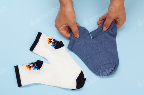 Preview: Female Hands With Pair Of Women Socks On A Blue Background, Top View.