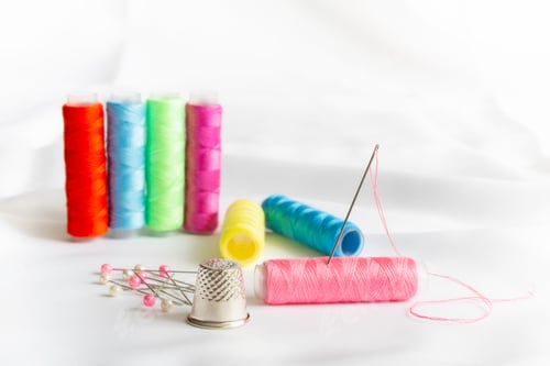 Preview: Needle, Pins, Thimble And Differently Colored Spools Of Thread On A White Background