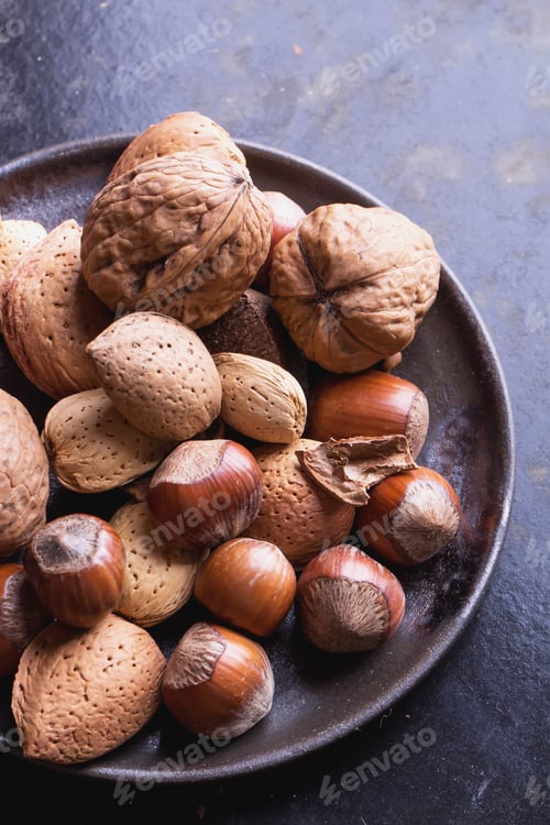 Preview: Selection Of Various Nuts In The Vintage Ceramic Plate, Black Background, Top View