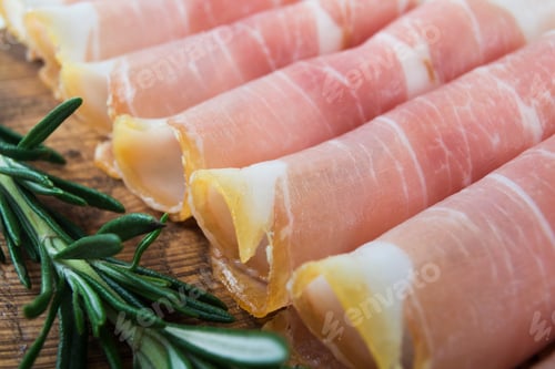 Preview: Slices Of Italian Prosciutto With Rosemary On Old Wooden Background.