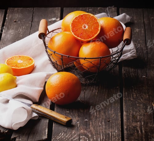 Preview: Bio Bloody Oranges And Lemons In The Basket On Rustic Wooden Board, Cut In Halves. Top View