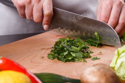 Preview: Young Woman Slicing Herbs In A Gray Apron
