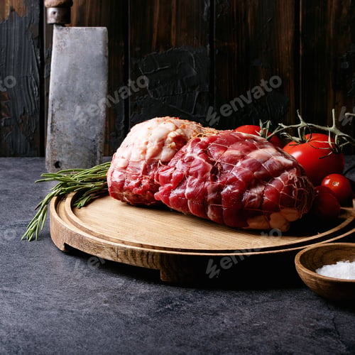 Vista previa: Raw Pork Meat On Wooden Round Board Served With Tomatoes, Salt, Pepper And Olive Oil Over Blue