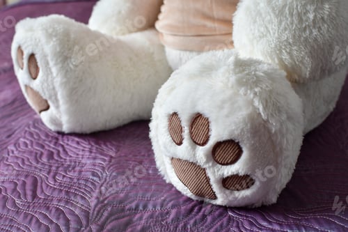 Preview: Close Up Of The Paw Of Big White Teddy Bear On The Purple Fabric. Selective Focus.