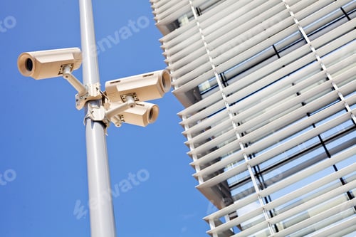 Preview: Closeup Of Three Surveillance Cameras On The Pole, Building And Sky In Background