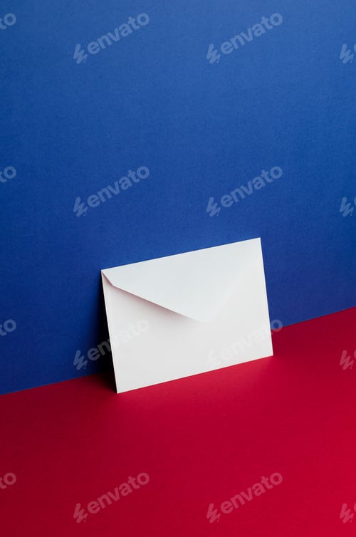 Preview: Envelope Tilted Over Blue And Red Background With Negative Space