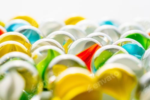 Preview: Yellow, Green, Blue And Red Glass Marbles On A Table.