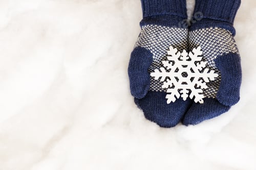 Preview: Woman Hands In Light Teal Knitted Mittens Are Holding Snowflake On Snow Background. Winter And