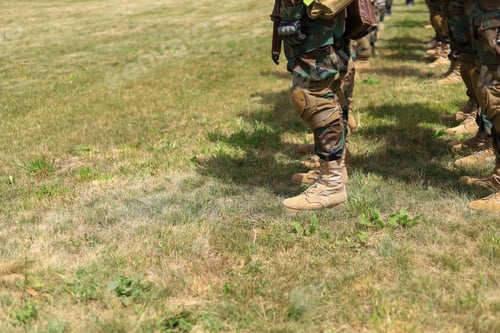 Preview: Legs Of Real Soldiers In Military Boots And Clothes Standing In Formation On The Grass. Background