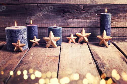 Preview: Bright Golden Stars And Black Burning Candles On Aged Wooden Textured Background. New Year
