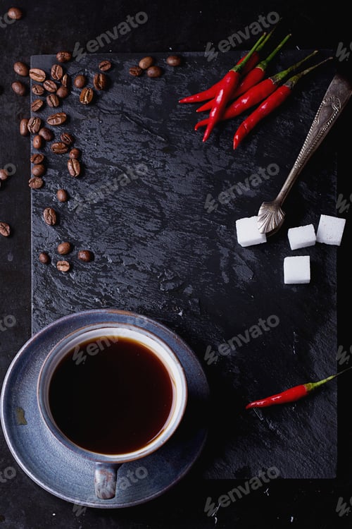Preview: A Cup Of Coffee On Black Slate Board With Chili, Coffee Beans, Sugar And Tiny Sugar Tongs. Top View