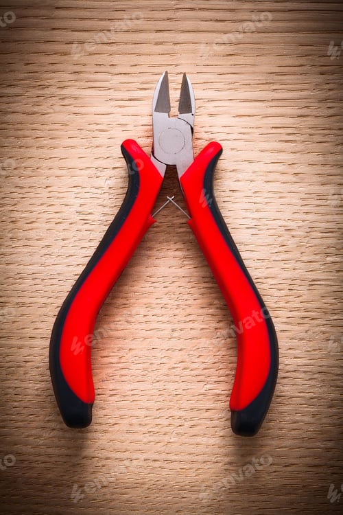 Preview: Aerial View Small Nippers With Black Red Handles On Wooden Board