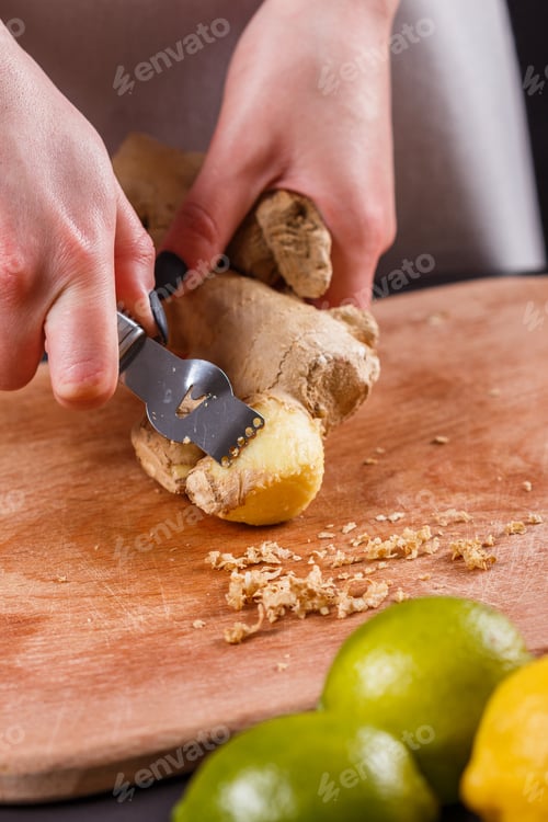 Preview: Young Woman In A Gray Apron Peeling A Ginger Root