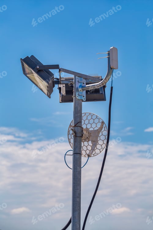 Preview: Wifi Antenna Outdoor On A Metal Light Pole With Blue Sky Background.