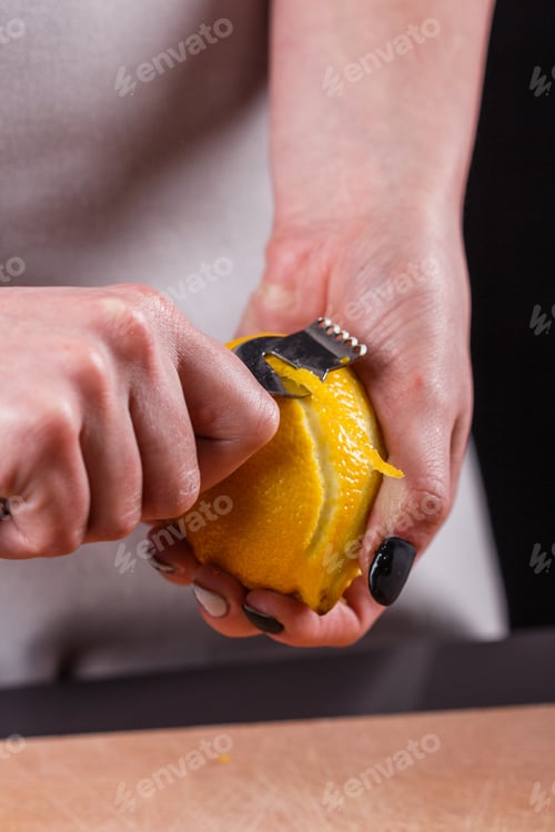 Preview: Young Woman In A Gray Aprons Cuts Lemon Zest