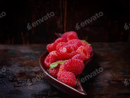 Preview: Fresh Organic Raspberries On Vintage Curvy Plate Over A Rustic Wooden Background.
