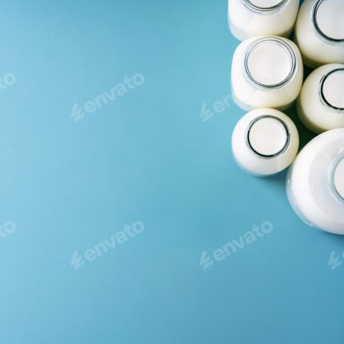 Preview: Fresh Milk In Different Glass Bottles Over Blue Texture Background. Copy Space. Eco Friendly