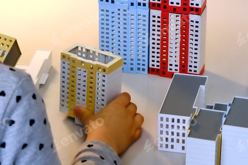 Preview: Children'S Hands Hold A Model Of A Modern Building To Create A Layout Of A City Or Street