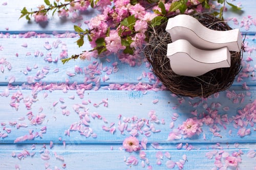 Preview: Pink Sakura Flowers And Two White Wooden Decorative Birds In Nest On Blue Wooden Planks. Selective