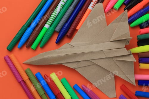 Preview: Origami Paper Airplane Mockup. Selective Focus. A Lot Of Multi-Colored Felt-Tip Pens On A Blurry