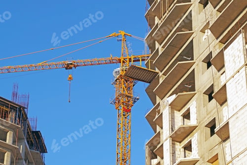Preview: Building Crane And Building Under Construction Against Evening Blue Sky