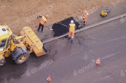Preview: Workers Fill A Hole In The Sidewalk Laying New Asphalt From The Bucket Of A Bulldozer
