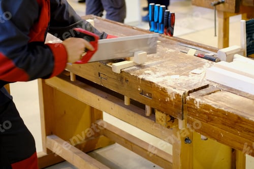 Preview: A Carpenter Cuts A Piece Of A Wooden Bar On A Workbench With A Saw