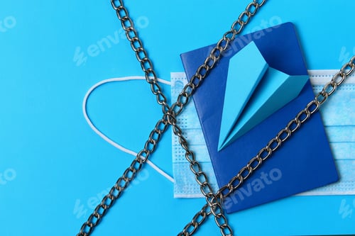 Preview: Paper Airplane And Passport On A Blue Background With A Medical Mask And Chains