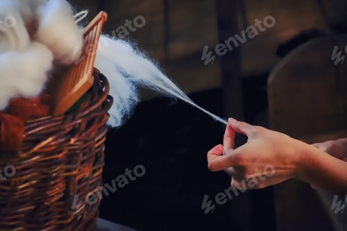 Preview: A Woman'S Hand Pulls Yarn From A Wicker Basket. Spinner Creates A Thread Of White Wool.