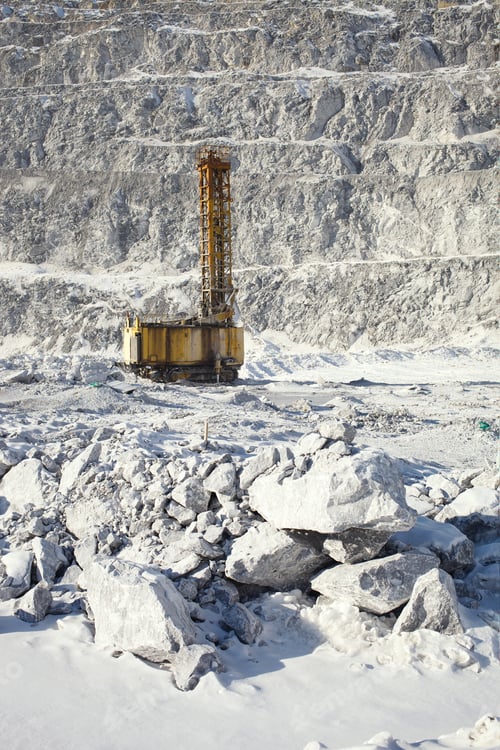 Preview: Drilling Machine In A Snow-Covered Stone Quarry With Fragments Of Stone In The Foreground.