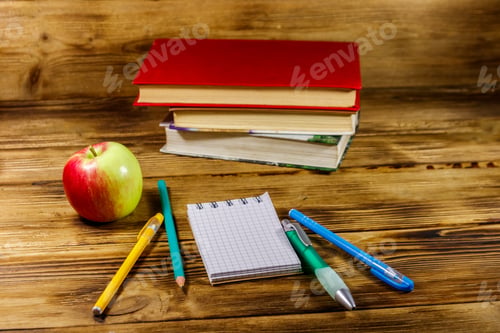 Preview: Stack Of Books, Notepad, Pens, Pencils And Apple On Wooden Desk. Back To School Concept