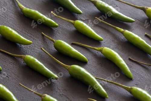 Preview: Green Hot Chili Peppers On Black Dark Background On Black Table. A Lot Of Chilli Peppers. Copy