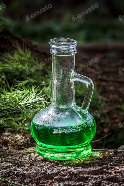 Preview: Glass Vessel With Green Herbal Potion In The Woods On The Trunk Of A Fallen Tree. Herbal And Magic