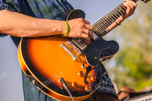Preview: Man Plays Orange Guitar Outdoors Under Blue Sky