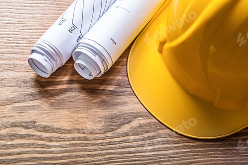 Preview: Rolled Engineering Drawings Hard Hat On Wooden Board Construction Concept.