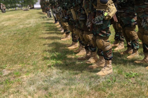 Preview: Legs Of Real Soldiers In Military Boots And Clothes Standing In Formation On The Grass. Background