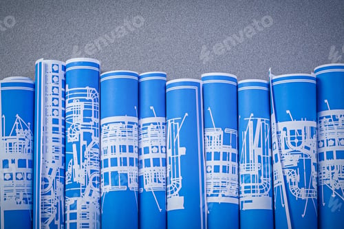 Preview: Collection Of Blue Rolled Up Engineering Drawings On Grey Background Construction Concept.