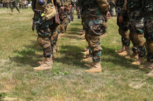 Preview: Legs Of Real Soldiers In Military Boots And Clothes Standing In Formation On The Grass. Background