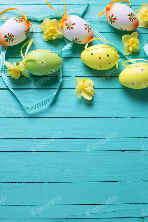 Preview: Border From Decorative Easter Eggs, Bright Spring Flowers And Ribbon On Bright Turquoise Wooden