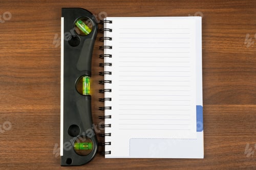 Preview: Builders Level With Note Pad On Brown Wooden Table, Top View