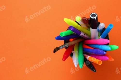 Preview: Stationery Glass With Felt Pens Top View. Orange Copyspace For Text Or Inscription.