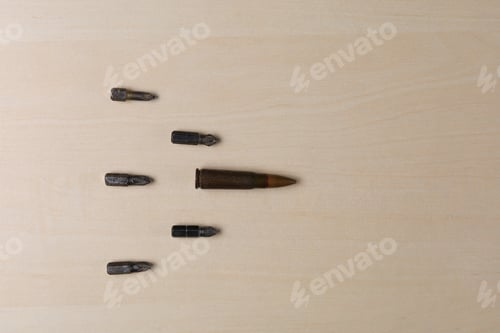 Preview: Military Rifle Bullet And Screwdriver Attachments On A Wooden Background. Abstract Concept Of Hard