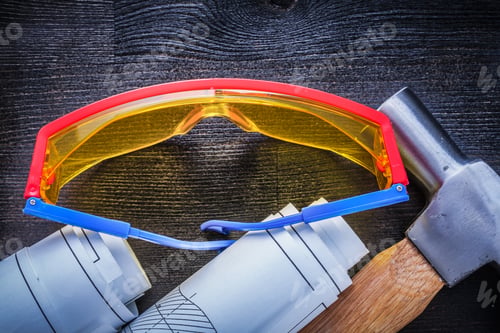 Preview: Close Up View Rolled Blueprints Hammer Goggles On Wood Board.