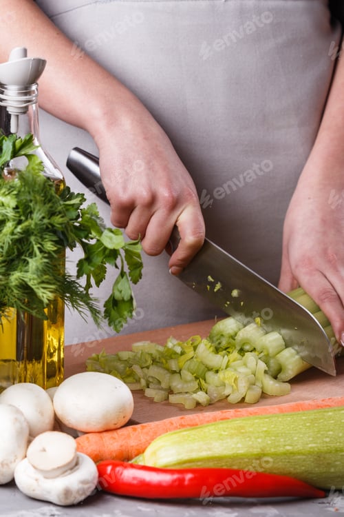 Preview: Young Woman In A Gray Apron Cuts A Celery