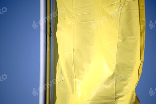 Preview: The Closeup Of A Yellow Waving Banner In Front Of Blue Sky Background.