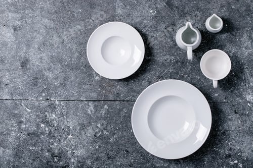 Preview: Variety Of Empty White Ceramic Plates And Bowls Over Dark Texture Background. Top View, Flat Lay