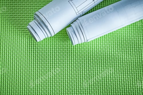 Preview: Rolled Up Construction Drawings On Green Surface Building Concept.