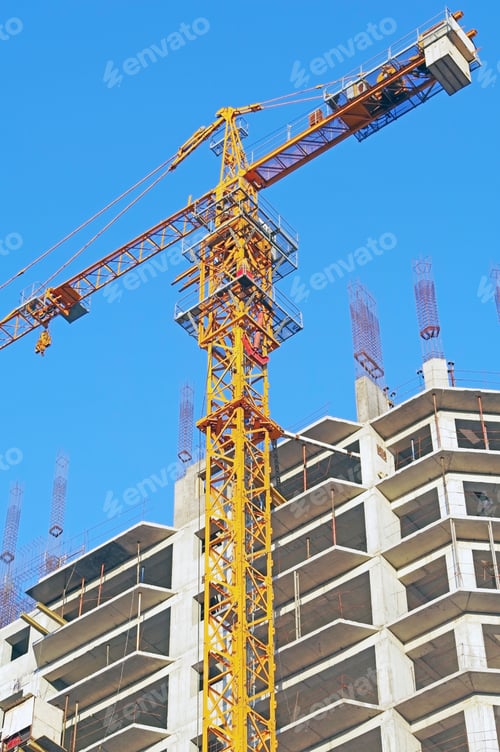 Preview: Building Crane And Building Under Construction Against Evening Blue Sky